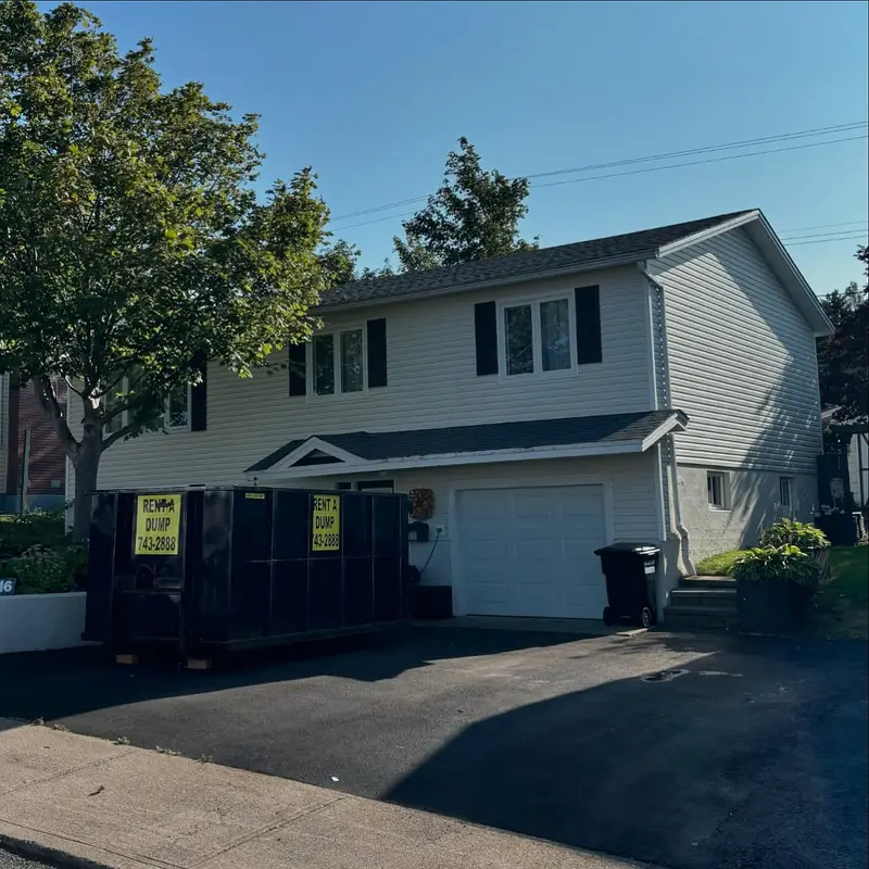 Two-storey house with a freshly shingled roof and a waste bin in the driveway