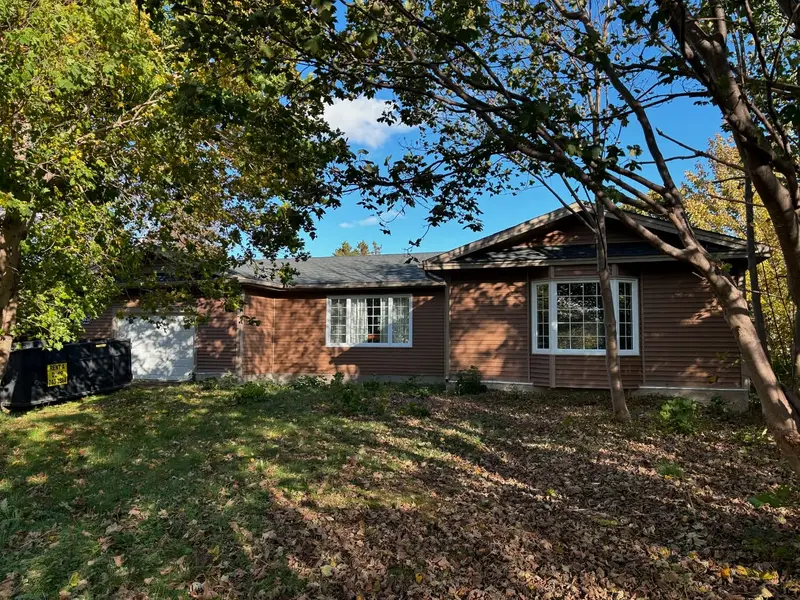 Brown house with a new shingled roof among autumn trees