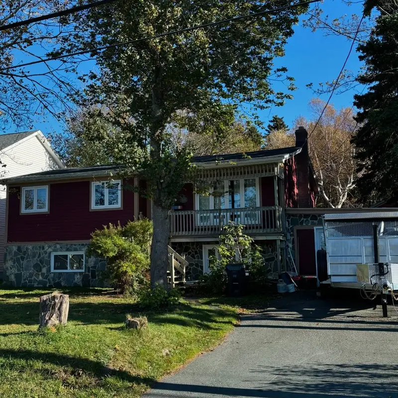 Red split-level house with a new roof surrounded by trees
