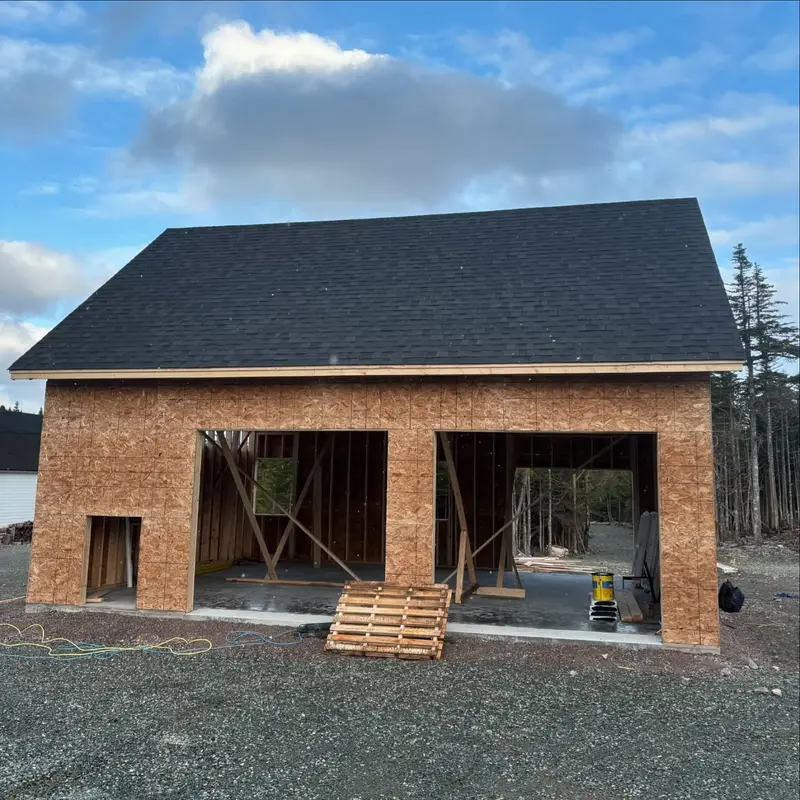 Newly framed garage with plywood walls and a new dark roof