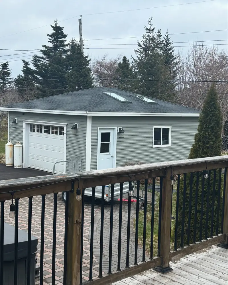 Grey detached garage with a new dark shingled roof