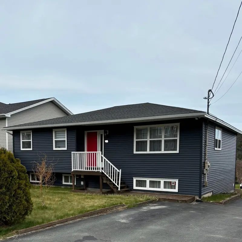 Bungalow with a dark roof and a red front door