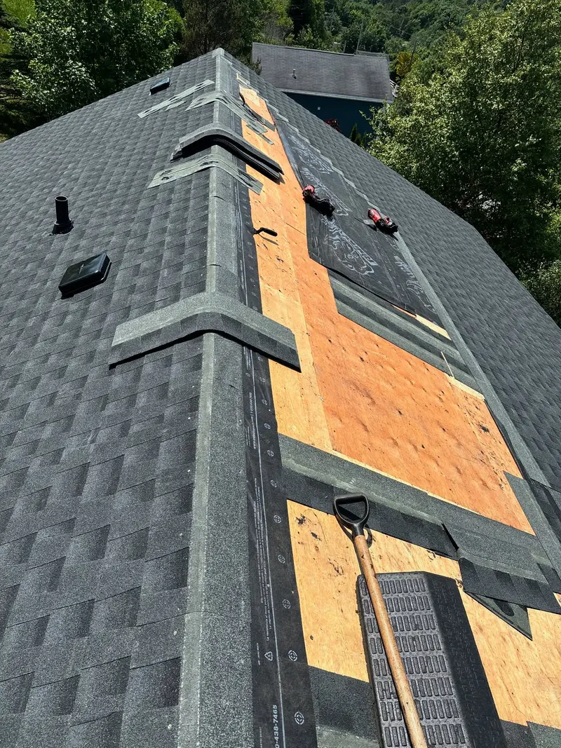 Close view of a roof partly shingled with bare plywood still showing