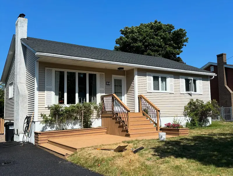 White bungalow with a new dark roof and a new wooden deck