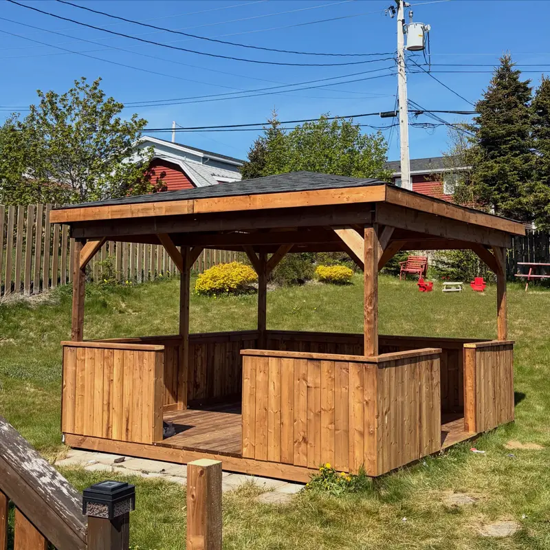 Wooden gazebo with a new dark shingled roof in a back garden